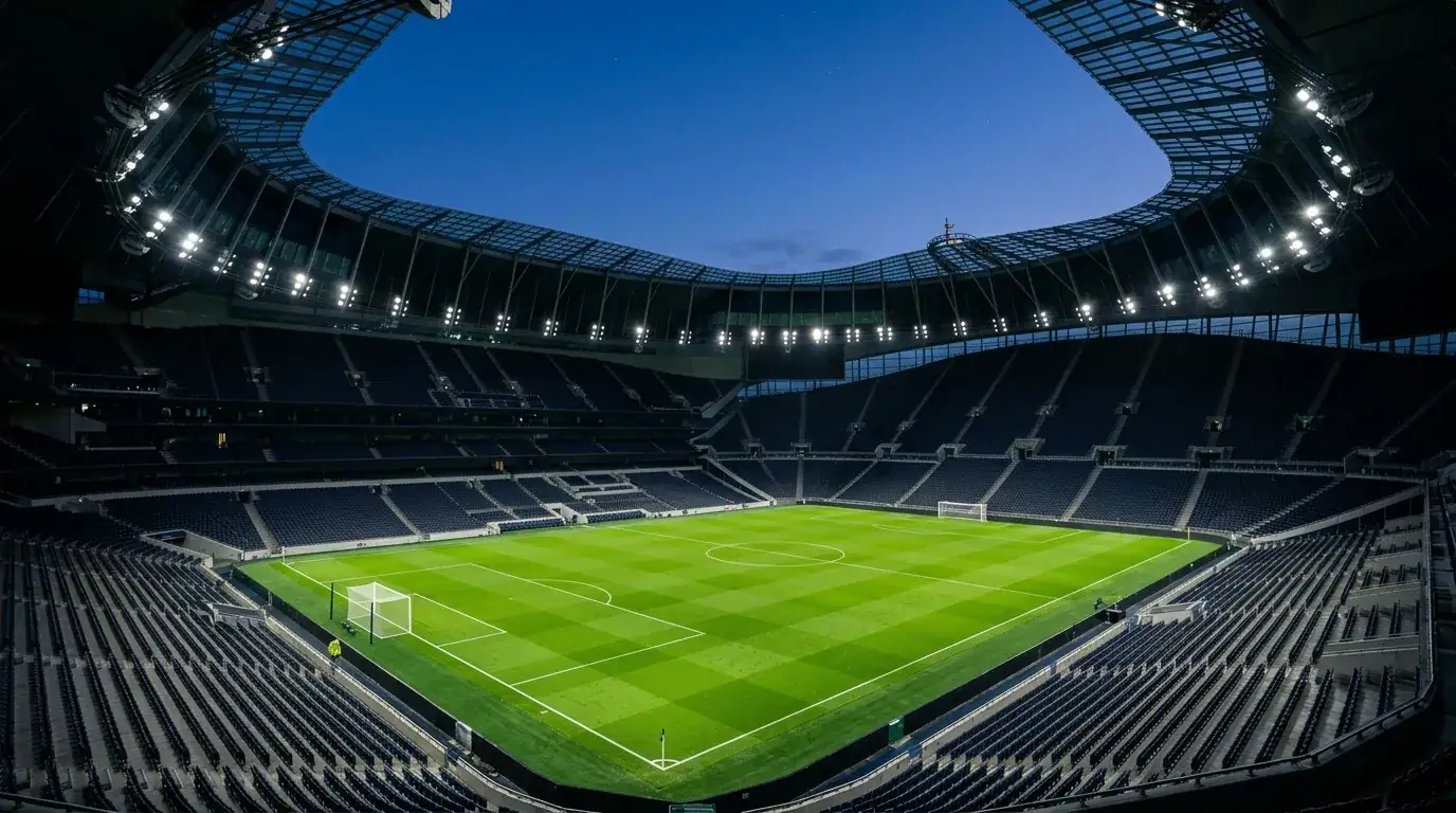 Prazen nogometni stadion z osvetljenim igriščem in praznimi tribunami pred tekmo